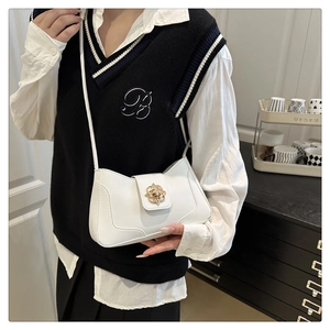 White mini crossbody bag with a gold flower buckle shown on a model for scale and style