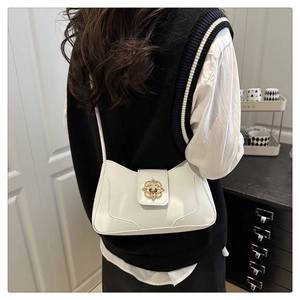 Close-up of a white patent leather shoulder bag featuring an elegant gold floral buckle