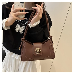 Detailed view of brown leather underarm bag featuring vintage gold floral buckle and knotted strap