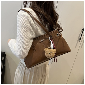 Détail du sac cabas en cuir ciré vintage avec barre en métal et breloque ours