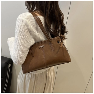 Détail du sac cabas marron foncé montrant la bandoulière et l'étiquette sur pull chaud