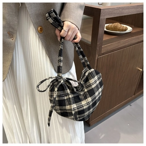 Gros plan du sac cabas en laine à carreaux noir et blanc avec un nœud décoratif assorti