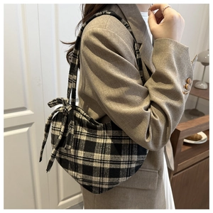 Vue détaillée d'un sac à carreaux noir et blanc avec nœud porté sur une veste grise