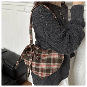 Close-up of red plaid heart-shaped wool bag with bow details on a fashion model