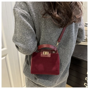 Detail of burgundy crossbody bag with suede patchwork and gold buckle closure