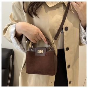 Close-up of golden metal twist lock on vintage dark brown suede crossbody bag