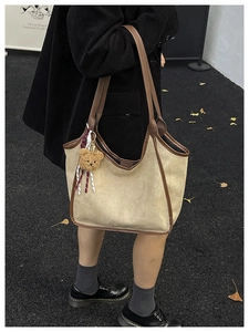 Detail of vintage beige suede tote bag with brown leather trim and cute bear charm