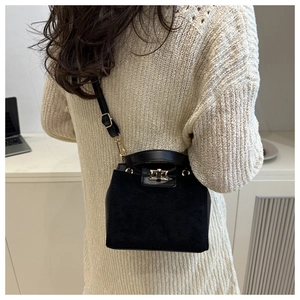 Detail of a black crossbody bag with matte suede texture and golden twist lock closure