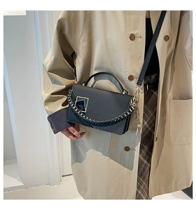 Tenue avec un sac à bandoulière en cuir noir muni d'une boucle dorée et chaîne