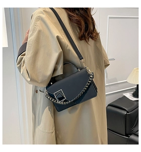 Detail of minimalist black crossbody bag with gold buckle and accordion fold design