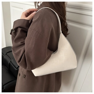 Close-up of minimalist cream leather underarm bag with debossed logo and metal zipper