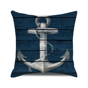 Détail de housse de coussin nautique avec ancre blanche sur texture grain de bois bleu