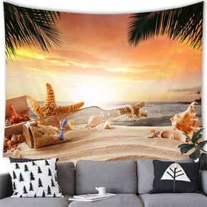 Detail of beach sunset tapestry hanging above a grey sofa with shells and palm leaves