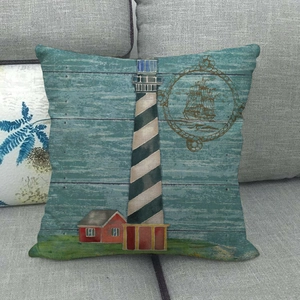Linen cushion cover with nautical lighthouse and sailboat print on a gray fabric sofa