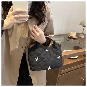 Detail of quilted handbag with white bow embroidery and contrasting brown leather trim