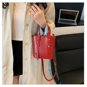 Detail of red PU leather bucket bag with top handles and adjustable shoulder strap