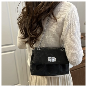 Gros plan d'un sac à chaîne noir au fini velours avec boucle en strass sur un mannequin