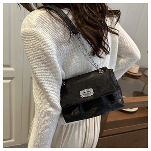 Detail view of black marble texture handbag with rhinestone buckle and silver chain strap