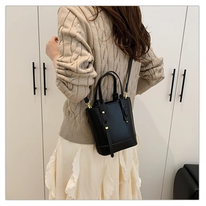 Sac seau noir minimaliste porté en bandoulière sur un modèle pour guide de taille