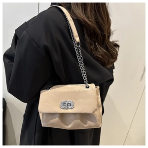 Détail du sac à chaîne beige avec texture suédée et fermoir rotatif serti de diamants