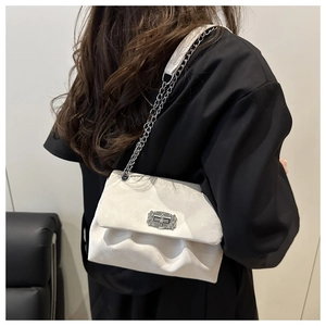 Détail d'un sac à bandoulière en velours blanc crème avec chaîne sur un mannequin