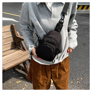 Détail de sacoche noire en nylon avec poches zippées et boucle de fermeture rapide