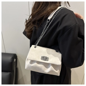 Detail of ivory velvet pleated bag featuring a silver clasp and chic metal chain strap
