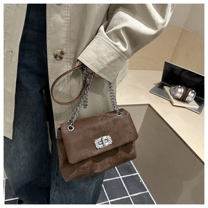 Macro detail of dark brown suede chain bag with sparkling rhinestone studded twist lock