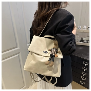 Detail view of cream faux leather backpack with silver turn-lock and cute bunny charm
