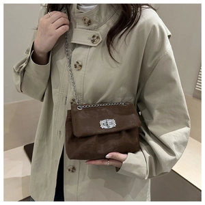 Nahaufnahme der braunen Wildleder-Umhängetasche mit Strass-Schnalle und silberner Kette
