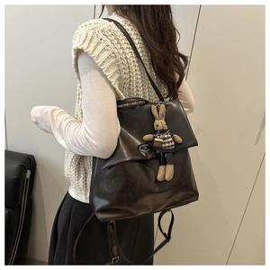 Detail of dark brown leather backpack with metal buckle and cute bunny plush charm