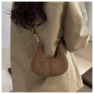 Detail of dark brown suede hobo bag with adjustable gold buckle on crescent strap