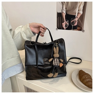 Detail of black faux leather tote bag with cute rabbit charm and metal turn-lock closure
