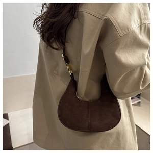 Detail of dark brown suede crescent bag worn over a trench coat for a stylish look