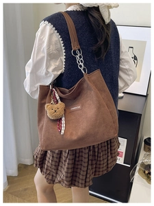 Détail du sac cabas en velours marron avec bandoulière en cuir et pendentif ours