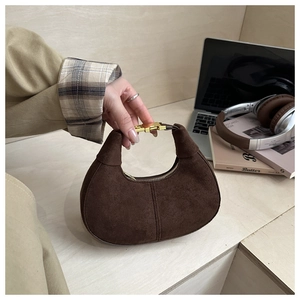 Detail of a dark brown suede crescent hobo bag with a gold metal buckle closure