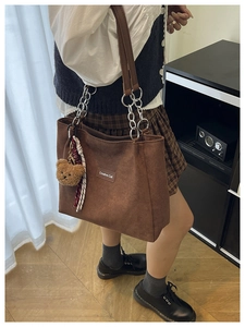 Détail du sac cabas en daim marron avec étiquette Creative Cat et bandoulières chaîne