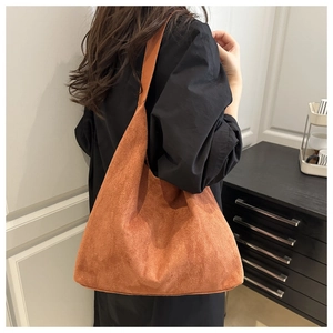 Brown suede tote bag shown on shoulder over black trench coat for minimalist style