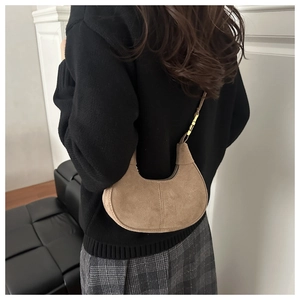 Detail of brown suede crescent bag with stitching and adjustable gold buckle strap