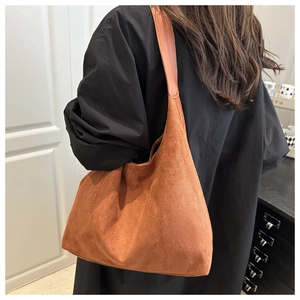 Detail view of a large brown suede tote bag with wide strap worn over the shoulder