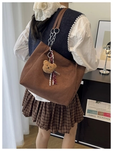 Détail du cabas en toile marron foncé avec lanières en cuir et pendentif ours en peluche
