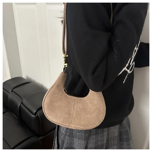 Detail of brown suede crescent bag with vertical stitching and gold metal hardware