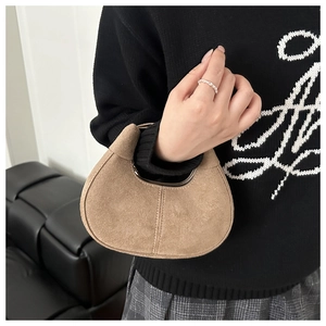 Close-up of brown suede crescent bag featuring a stylish knotted handle and zipper detail