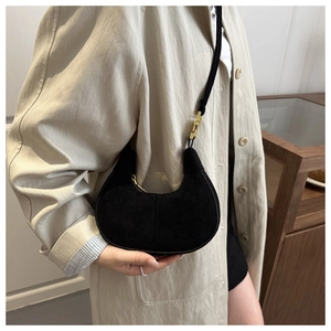 Macro detail of black matte crescent bag with gold buckle on beige stylish coat