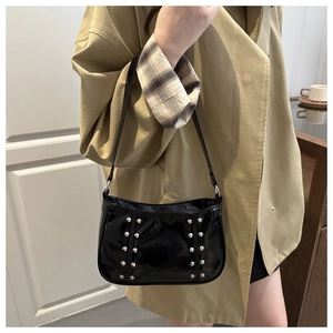 Détail du sac bandoulière en cuir verni noir avec clous argentés et style rétro