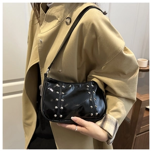 Détail du sac sous le bras en cuir verni noir avec rivets argentés sur un trench-coat
