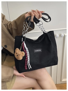 Détail du cabas en velours côtelé noir avec bandoulière chaîne et ours en peluche