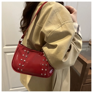 Détail du sac porté épaule en cuir rouge brillant avec clous argentés sur un mannequin