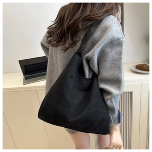 Chic black matte suede tote bag shown on shoulder with casual knitwear for daily style