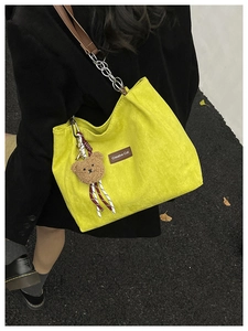 Détail du sac cabas en velours côtelé jaune avec patch cuir, ourson et sangle en chaîne